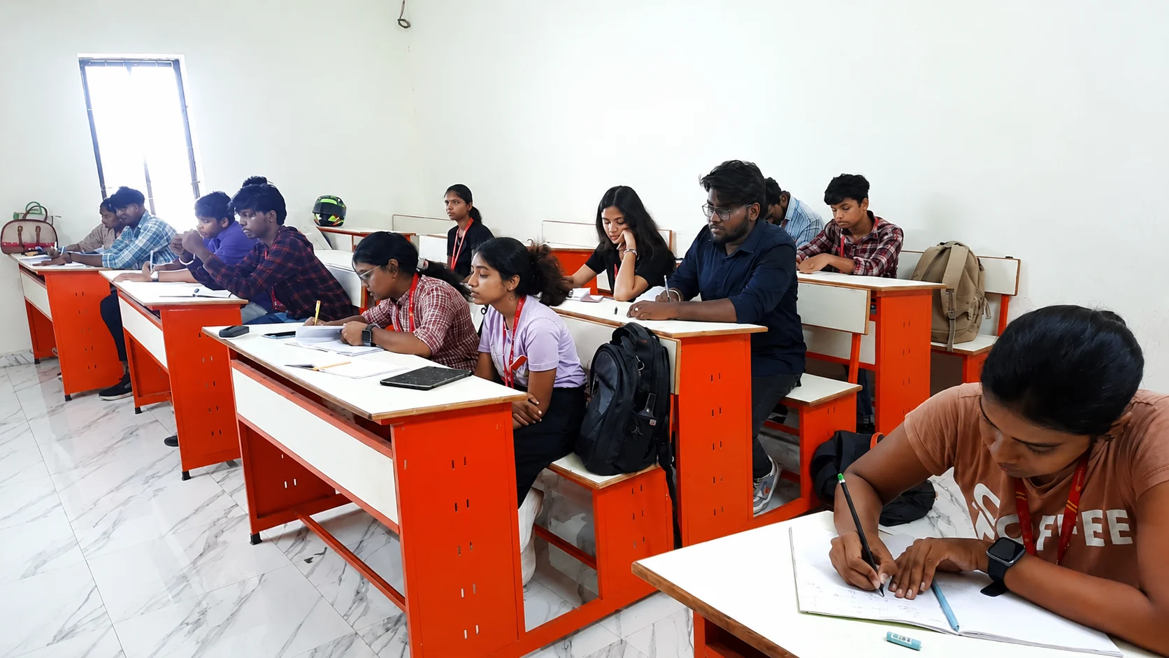 Students seated at desks writing notes in a college classroom